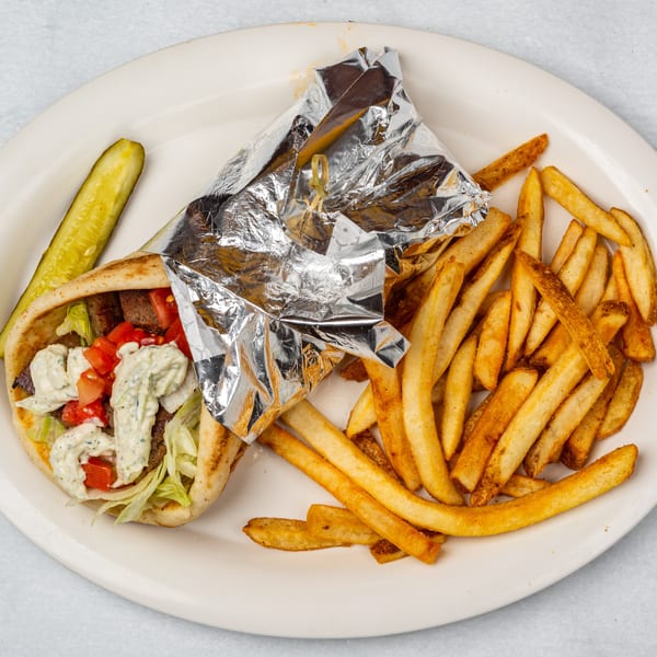 Oakcrest Family Restaurant's gyro with fries and a pickle spear on a white plate.