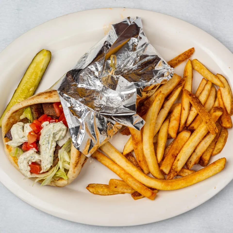 Oakcrest Family Restaurant's gyro with fries and a pickle spear on a white plate.